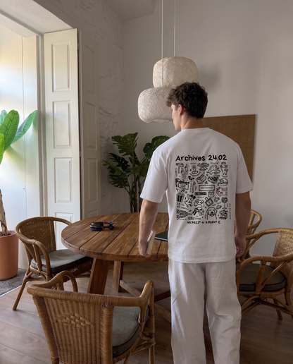 Photo d'un homme de dos portant le t shirt Archives de la marque Koeur Indigo réunissant tous les souvenirs avec sa copine et où il y a le texte personnalisé "Archives 24.02" et les coordonnées GPS du lieu de leur rencontre. 
